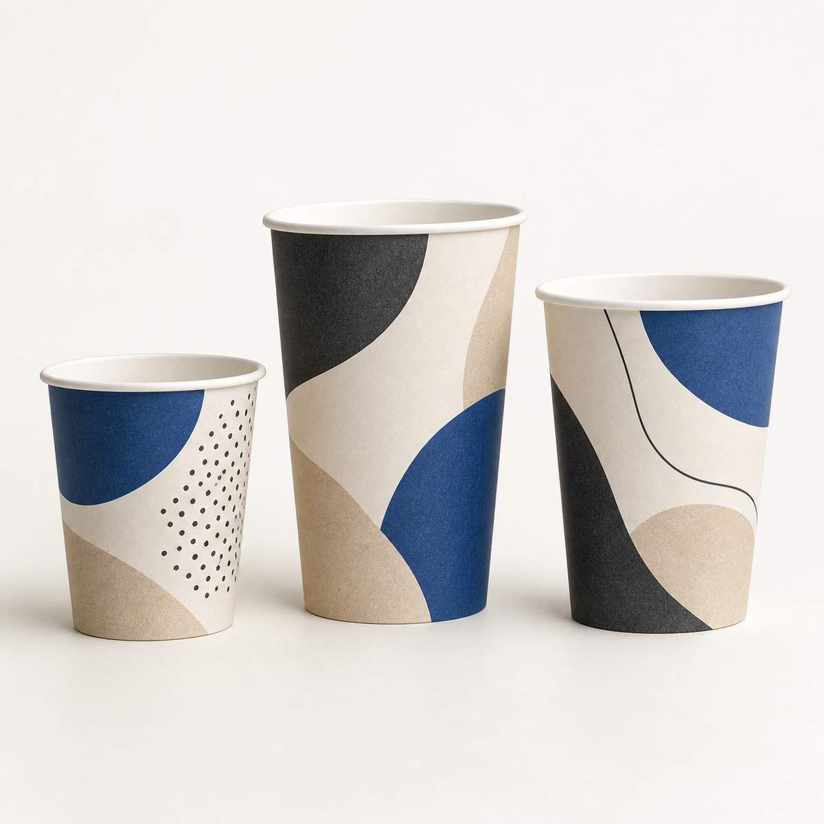 Custom printed paper cups in three sizes on a neutral studio background